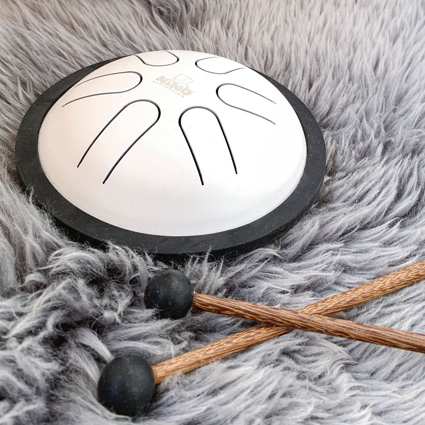 Weiße NINO980WH Mini Steel Tongue Drum mit schwarzem Rand und zwei Schlägeln auf Fellunterlage